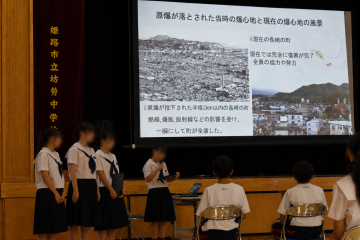 体育館で、生徒たちがスライドを使って原爆投下後の様子を説明しています。