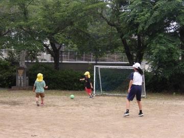 幼児と中学生がサッカーをする様子