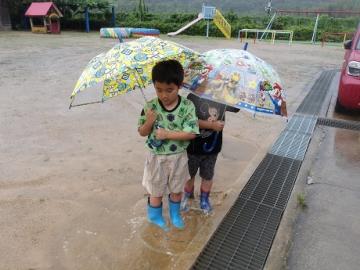 幼児が雨の中水たまりに入っている様子