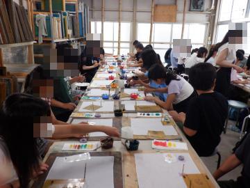 長机に沿って学生が座り道具や紙を使って工作や製図に集中している様子