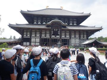 生徒たちが伝統的な大型の木造寺院の前に立っている風景