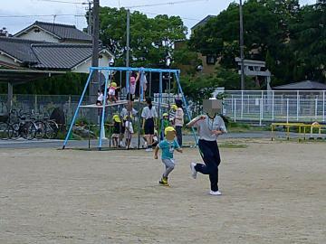 中学生と児童が園庭で追いかけっこをして遊んでいる様子