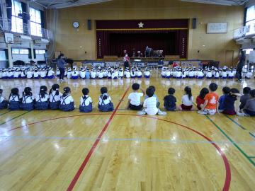 体育館で、飾磨小学校1年生の音楽会練習風景を床に座って見学している様子