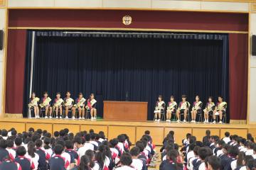 体育館の舞台上に並ぶ候補者と体育館の床に全校生徒が座っている様子2