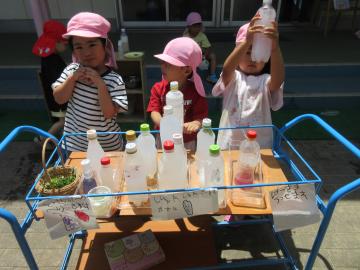 園庭で、完成した色水を見せている園児たちの様子