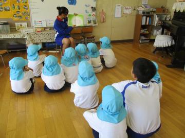 中学生が幼児に絵本を読み聞かせをしている様子