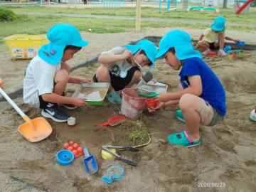 幼児が砂場で友達と一緒に遊んでいる様子