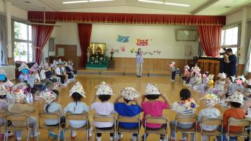園の遊戯室で兜をかぶった園児が椅子に座っている