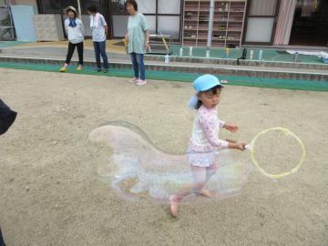 女の子が一人、大きなシャボン玉を作りながら走っている様子