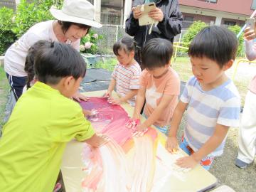 机の上の絵具を手でまぜることを楽しんでいる様子