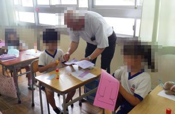 教室内で公民館長が児童へ紙衣を教えている様子