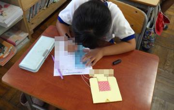 男子児童が机の上に置かれた短冊に願い事を書いている様子