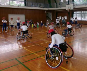 体育館で、車いすバスケットをする前に練習をしている児童たちの様子