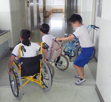 校舎4階の廊下で、児童たちが車いすで廻ることに取り組んでいる様子