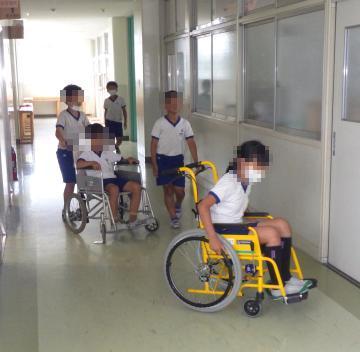 まっすぐに廊下を車いすで渡ろうとする児童たちの様子