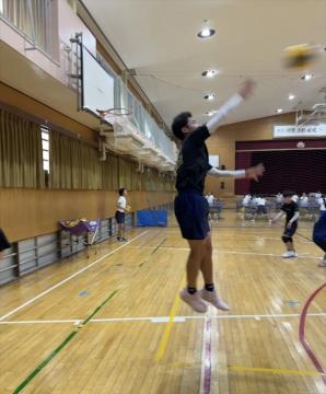 屋内の体育館でジャンプしてボールを放る選手がいるバスケットボールの練習風景