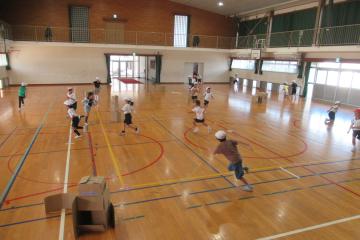 学活の時間に体育館で2年生が追いかけっこをしている様子
