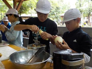 5年生が屋外で班ごとにカレーに入れる食材を調理している様子