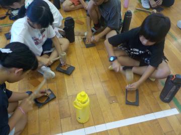 5年生が体育館でレザークラフト体験で小銭入れ作りをしている様子