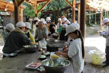 5年生が飯盒炊爨で野菜を切る様子
