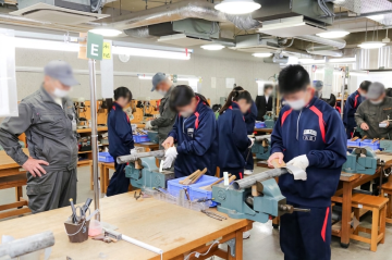 生徒たちがテーブルにある機械を使って作業をしている様子