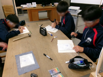 生徒がテーブルを囲んでノートやタブレットを使って作業をしている様子
