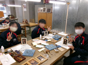 作成した銅板をカメラに向けてピースサインをする生徒3名
