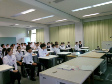 講堂で席に座って講義を聞く生徒達