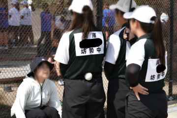 屋外で、女子ソフトテニス部員2名が監督からの指示を確認している様子です。