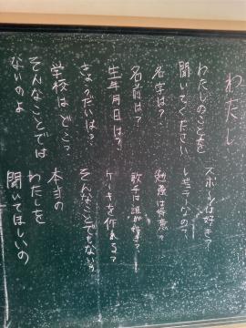 黒板に縦書きの日本語の詩のような白いチョークの文字が複数列並んで書かれている教室の一角の写真