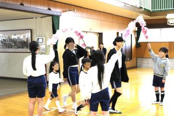1年生が6年生と手をつないで花道を通っていく様子