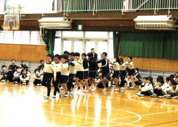 5年生が1年生のために肩を組んで1列に入場する様子