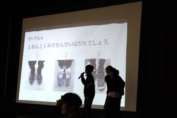 6年生が1年生をはじめとする全児童に三択クイズを出す様子