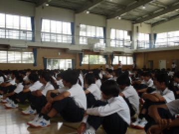 体育館で座り、終業式で話を聞く生徒たちの様子