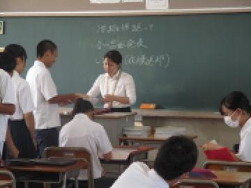 教室内で、学活で一人ずつ教師から通知表を受け取る生徒たちの様子