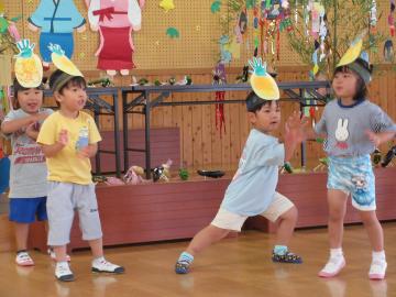 遊戯室でパイナップルのお面をかぶった子どもたちがダンスを披露している様子