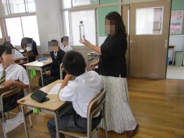 教室で、講師の方がペットボトルを使って生徒に説明しています。