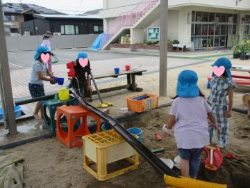 砂場にいろんな遊び道具を置いて遊んでいる園児たち
