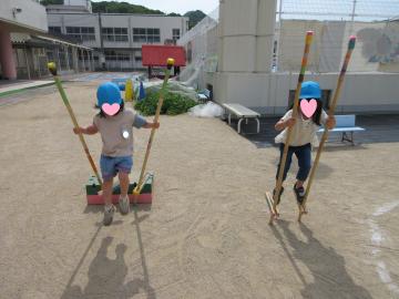 運動場で竹馬に乗って歩く園児の様子