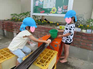 庭でそうめん流しをしている園児のようす