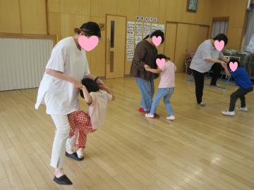遊戯室で親子がペアになって手を繋いで足踏みゲームをしている