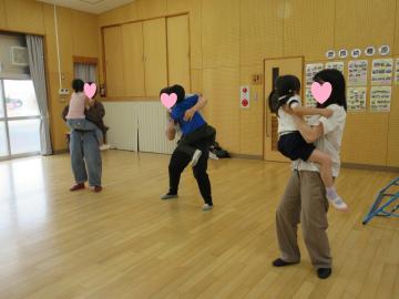 遊戯室でお母さんに抱っこしてもらっている園児たち