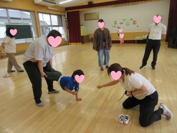 親が子供の足をもって子供は手で支えて、園長先生と子供がじゃんけんしているようす