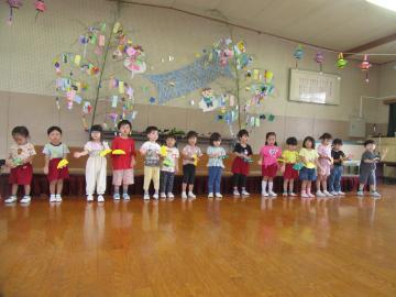 3歳児が自分たちで作ったカスタネットを使い、カエルの合唱のリズム遊びをしている様子