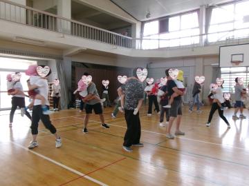体育館で親が子供を抱っこしながら運動している