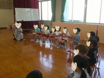 4歳児が打楽器をもって遊戯室の椅子に座っている