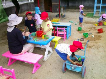 砂場で3歳児がままごと遊びをしているところ