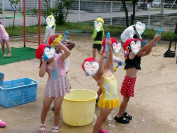 屋外で3歳児たちが水鉄砲をして遊んでいる様子