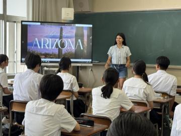 教室内で、英語の授業中に生徒たちの前でプレゼンテーションする交換留学生の様子