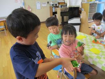 夏野菜で作ったお供え物を友第と見せ合っている様子